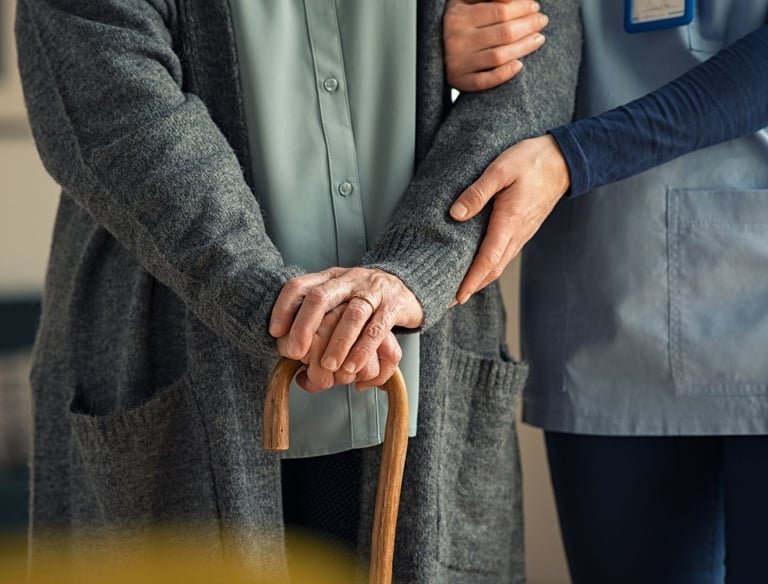 Caregiver supporting an elderly woman with a cane