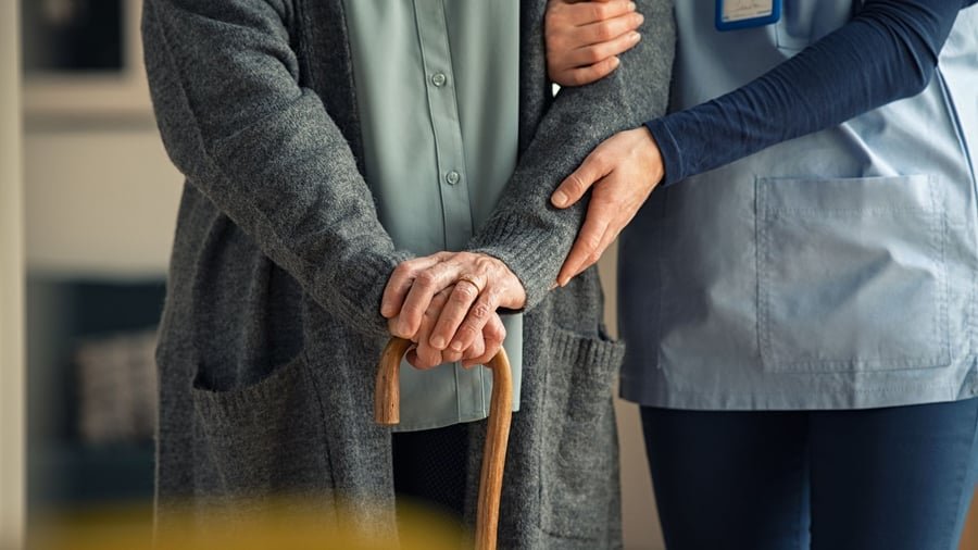 Ezra Healthcare caregiver supporting an elderly woman with a walking cane